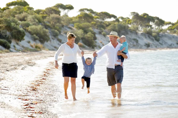 Young happy beautiful family walking together on the beach enjoying summer holidays — Stock Photo, Image