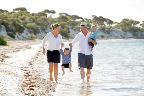Fiatal boldog szép család, gyaloglás együtt a nyári szünetben a tengerparton — Stock Fotó