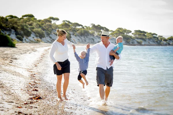 Jovens família bonita feliz andando juntos na praia desfrutando de férias de verão — Fotografia de Stock