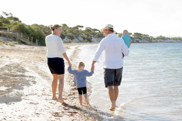 Young happy beautiful family walking together on the beach enjoying summer holidays — Stock Photo, Image