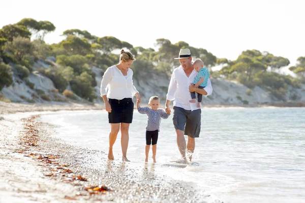 Joven feliz hermosa familia caminando juntos en la playa disfrutando de vacaciones de verano — Foto de Stock