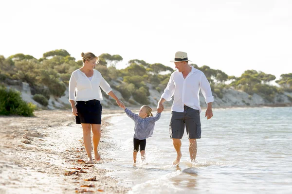 年轻的快乐母亲和父亲在家庭度假概念在沙滩上行走 — 图库照片