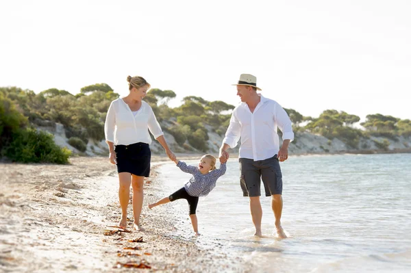 年轻的快乐母亲和父亲在家庭度假概念在沙滩上行走 — 图库照片