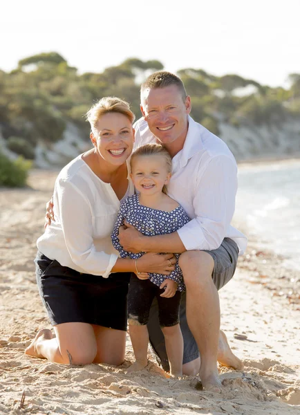 Hermosa familia pareja esposa y marido sosteniendo pequeña hija en la playa — Foto de Stock