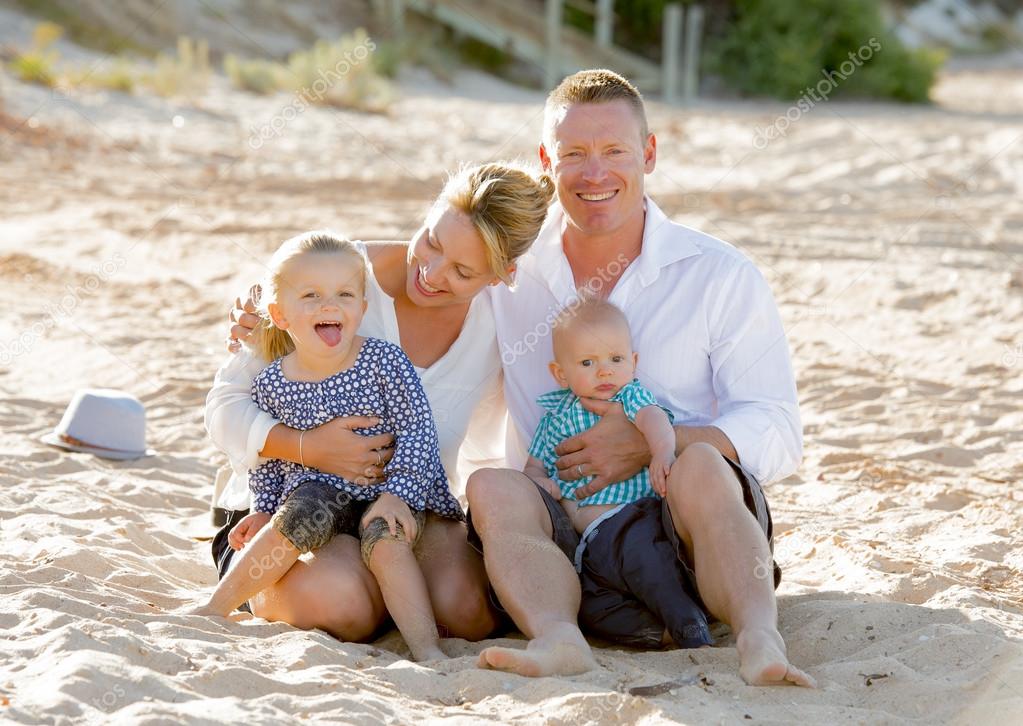  happy family couple sitting on beach sand with baby boy son and daughter 