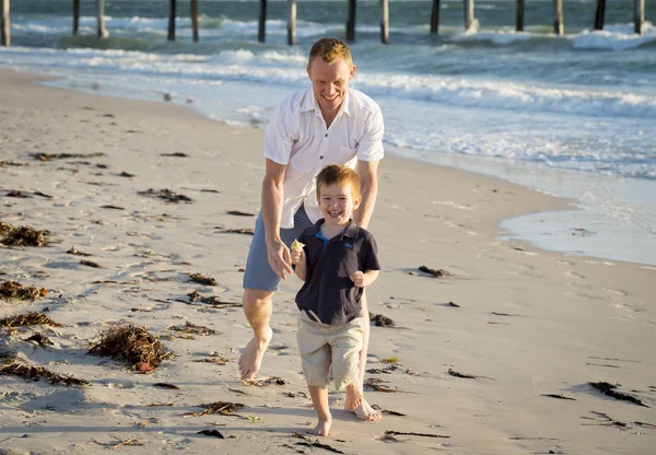 快乐爸爸玩在沙滩上与运行的小儿子兴奋与赤脚在沙子和水 — 图库照片