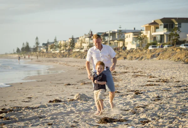 Lycklig far spelar på stranden med lille son kör exciteras med barfota i sand och vatten — Stockfoto