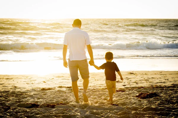 Happy father holding holding hand of little son walking together on the beach with barefoot — Stock Photo, Image