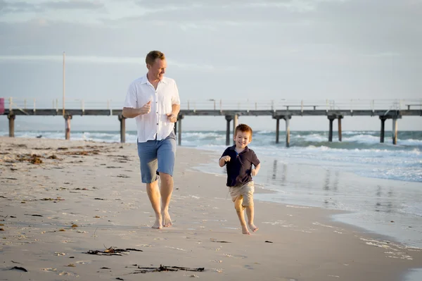 Happy father playing on the beach with little son running excited with barefoot in sand and water — Stock Photo, Image