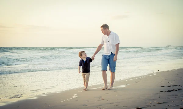 Heureux père tenant la main du petit fils marchant ensemble sur la plage avec pieds nus — Photo