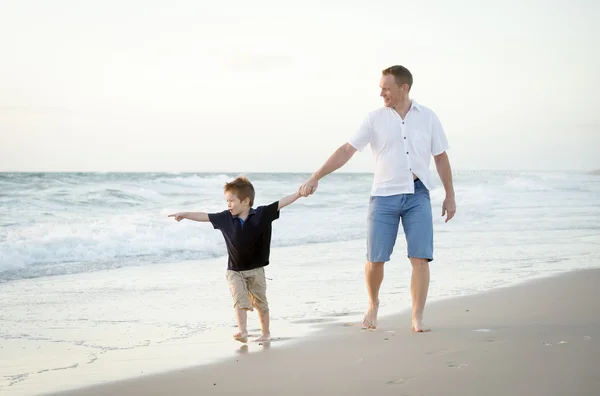 Heureux père tenant la main du petit fils marchant ensemble sur la plage avec pieds nus — Photo