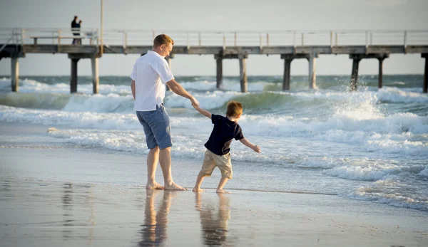 Heureux père jouer sur la plage avec petit fils courir excité avec pieds nus dans le sable et l'eau — Photo