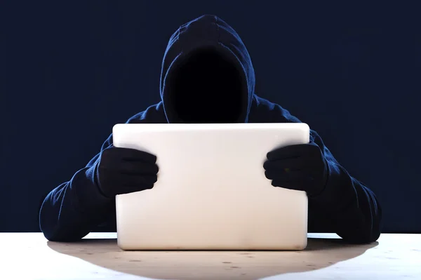 Hacker man in black hood and mask with computer laptop hacking system in digital intruder cyber crime concept — Stock Photo, Image