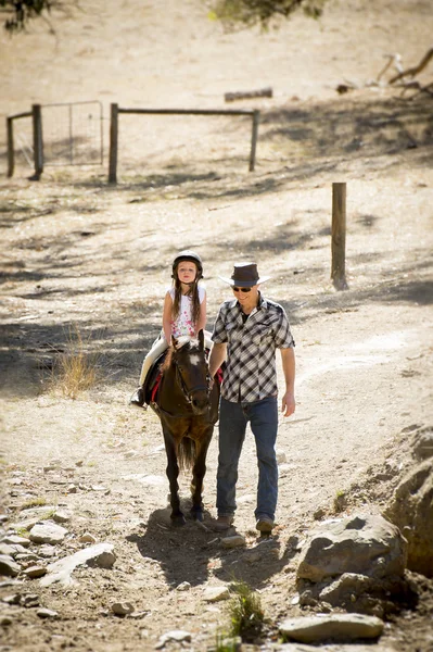 Jovem jockey miúdo equitação pônei ao ar livre feliz com o pai papel como instrutor de cavalo no cowboy olhar — Fotografia de Stock