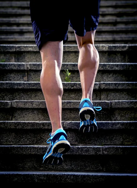 Young athletic legs with sharp scarf muscles of runner sport man climbing up city stairs jogging and running in urban training workout