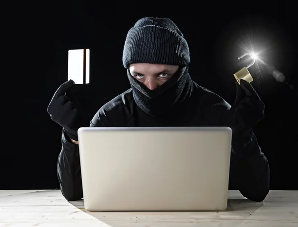 Man in het zwart holding creditcard en slot met behulp van computer laptop voor criminele activiteiten hacken bankrekening wachtwoord — Stockfoto