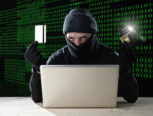 Man in black holding credit card and lock using computer laptop for criminal activity hacking bank account password — Stock Photo, Image