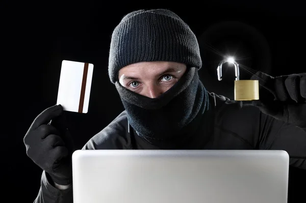 Mann in Schwarz hält Kreditkarte und Schloss mit Computer-Laptop für kriminelle Aktivitäten Hacker Bankkonto Passwort — Stockfoto