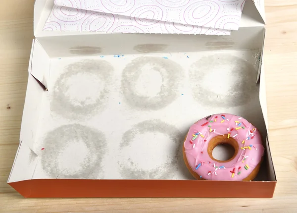 Empty cakes box with only one tempting and delicious donut with toppings left — Stock Photo, Image