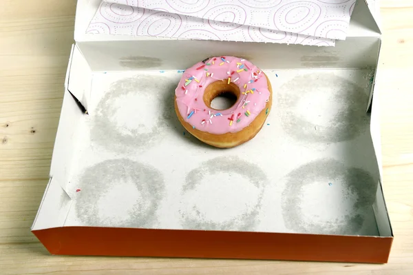 Tom kakor låda med endast en lockande och läckra donut med pålägg kvar — Stockfoto