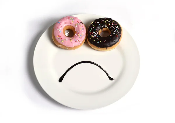 Smutną buźkę, wykonane na danie z pączków jak oczy i usta syrop czekoladowy w cukier słodki uzależnienia dieta i odżywianie — Zdjęcie stockowe