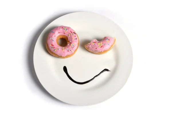 Smiley happy face made on dish with donuts blinking eye and chocolate syrup as smile in sugar and sweet addiction — Stock Photo, Image