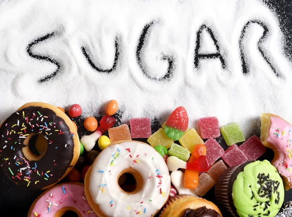 Mix of sweet cakes, donuts and candy with sugar spread and written text in unhealthy nutrition — Stock Photo, Image