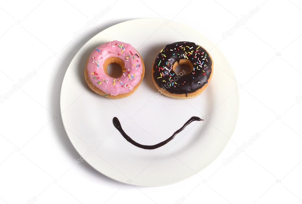 smiley happy face made on dish with donuts eyes and chocolate syrup as smile in sugar and sweet addiction nutrition