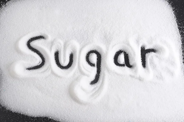 Woord geschreven met vinger op stapel van suiker in voeding, zoete overmatig gebruik en gezonde voeding concept geïsoleerd — Stockfoto