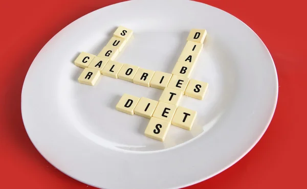 Juego de crucigramas en el plato en la mesa alfombra roja con palabras azúcar, calorías, diabetes y dieta tomando en el abuso de azúcar riesgo para la salud —  Fotos de Stock