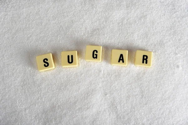 Letras de bloque de azúcar en crucigrama sobre pila de azúcar aislado en textura de azúcar blanca granulada en el abuso de alimentos dulces —  Fotos de Stock