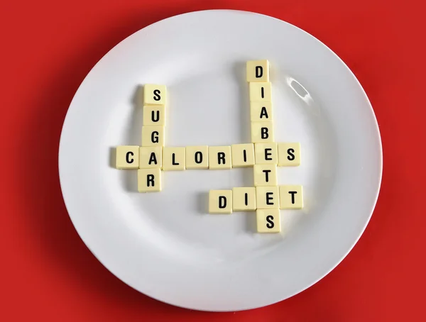 Crossword game on dish on table red mat with words sugar , calories, diabetes and diet taking in sugar abuse health risk — Stock Photo, Image