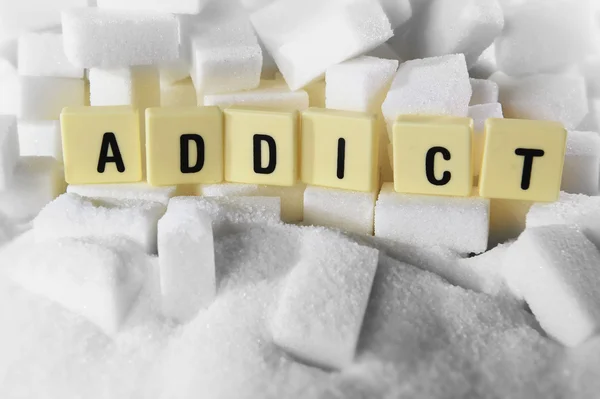 Addict drukletters woord op stapel van suikerklontjes close-up in suiker verslaving concept — Stockfoto