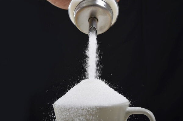 man hand with sugar bowl pouring a crazy lot in full coffee cup in addiction concept