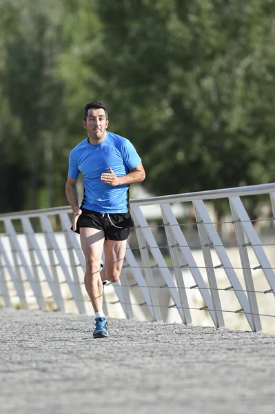 Lekkoatletycznego młody człowiek ćwiczyć bieganie i Sprint na tle park miejski miasta w treningu sportowego — Zdjęcie stockowe