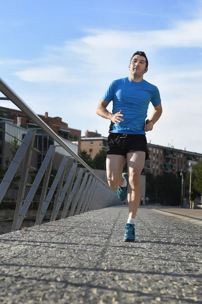 Young athletic man running on blue sky urban city background in sport training — Stock Photo, Image