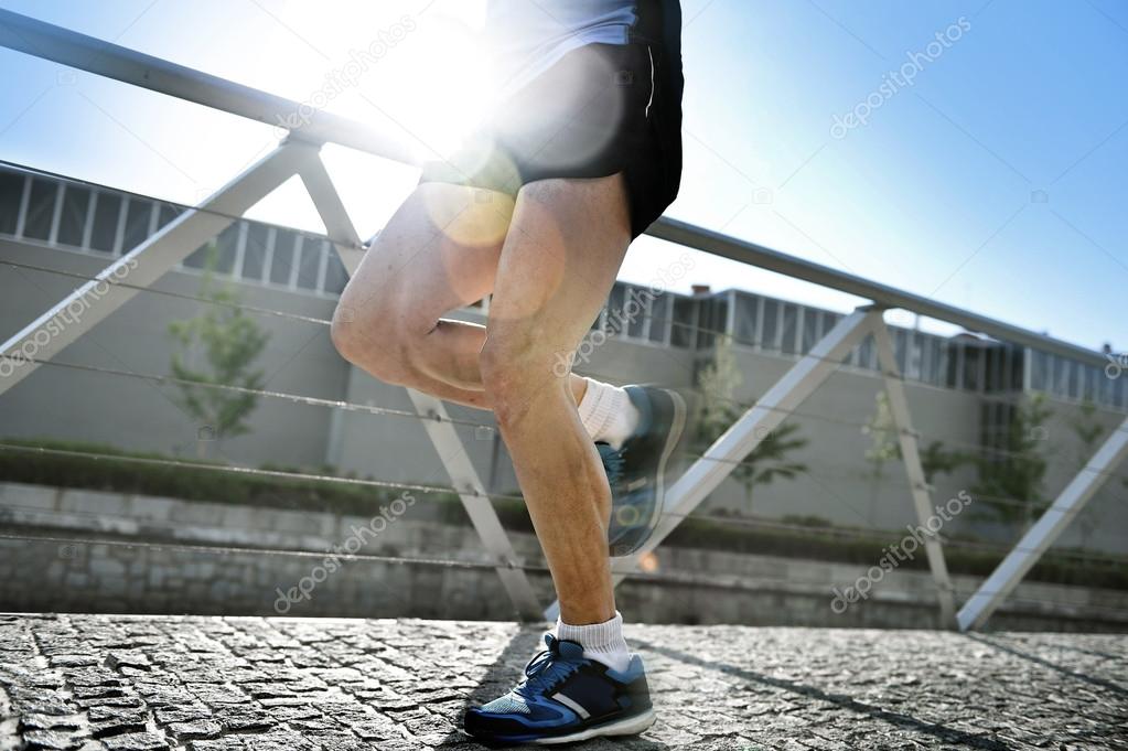 close up legs and shoes of young athletic man practicing running in urban background natural rising backlight