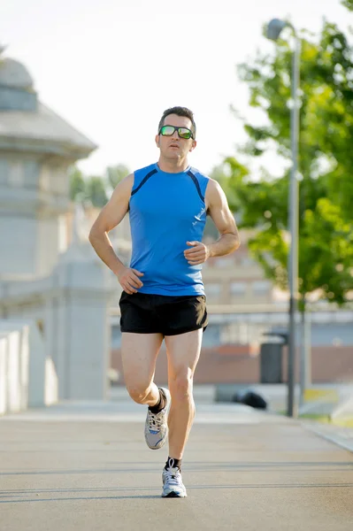 Jonge atletische man loopt op stedelijke stadspark in zomer sport trainingssessie — Stockfoto