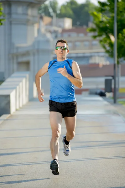 Jonge atletische man loopt op stedelijke stadspark in zomer sport trainingssessie — Stockfoto