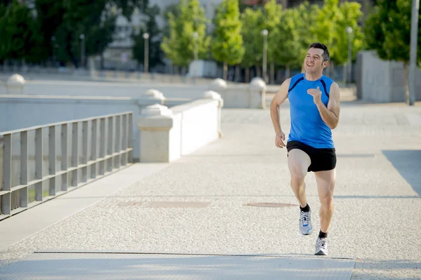 Jonge atletische man loopt op stedelijke stadspark in zomer sport trainingssessie — Stockfoto