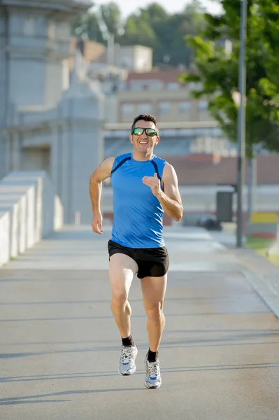 Jonge atletische man loopt op stedelijke stadspark in zomer sport trainingssessie — Stockfoto