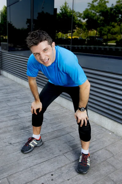 Young attractive man leaning exhausted after running session sweating taking a break to recover in urban street — Stock Photo, Image