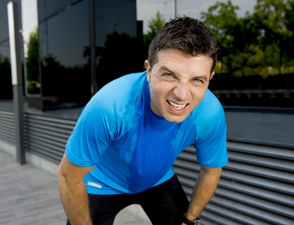 Young attractive man leaning exhausted after running session sweating taking a break to recover in urban street — Stock Photo, Image