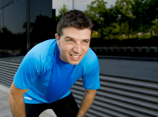 Young attractive man leaning exhausted after running session sweating taking a break to recover in urban street — Stock Photo, Image