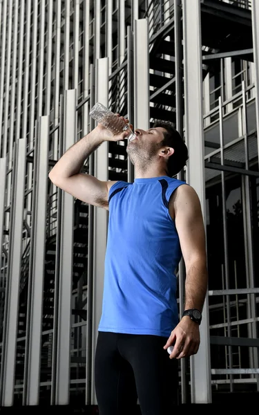 Junger Sportler trinkt Wasserflasche nach Lauftraining im Geschäftsviertel — Stockfoto