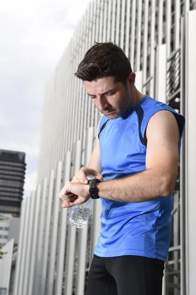 Young sport man checking time on chrono timer runners watch holding water bottle after training session — Stock Photo, Image