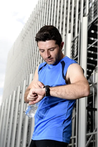 Junger Sportler überprüft Zeit auf Chrono-Timer-Läuferuhr mit Wasserflasche nach Trainingseinheit — Stockfoto