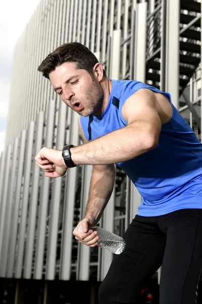 Sport man breathing exhausted after running leaning tired and checking timer watch — Stock Photo, Image