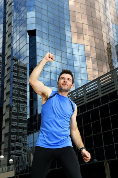 Vonzó sport férfi csinál győzelem és a győztes jele a karját, után futás képzés, városi üzleti negyedben — Stock Fotó