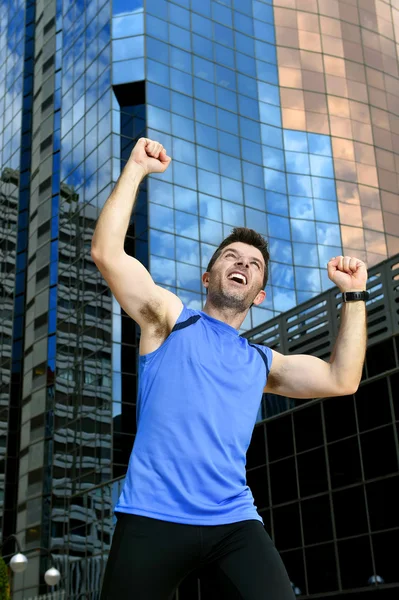 Atractivo deportista haciendo la victoria y el signo ganador con sus brazos después de correr la formación en el distrito de negocios urbanos — Foto de Stock